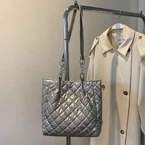 Detailaufnahme der gesteppten Tragetasche in Metallsilber mit dekorativen Metallketten