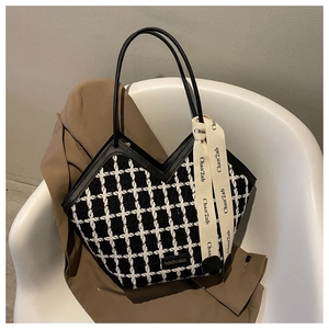Close-up of black and white plaid tote bag with leather handles and decorative silk scarf