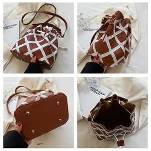 Detail view of plaid bucket bag with drawstring, long strap, and protective metal feet