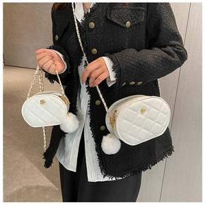 Close-up of white quilted leather chain bag featuring gold flower hardware and plush pompom