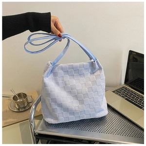 Gros plan sur le sac cabas bleu clair à motif damier sur un bureau de travail moderne