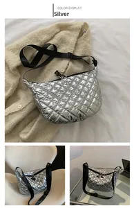 Detail of silver quilted hobo bag with wide strap on a beige knit sweater background