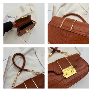 Detail of crocodile embossed leather handbag with golden twist lock and chain strap