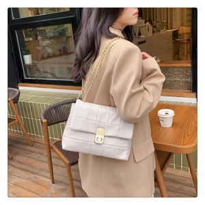 Close-up of white quilted chain bag with gold rotary lock and elegant metal strap