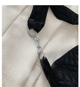 Detailed close-up of shiny silver metal chain hardware on a black quilted shoulder bag