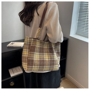 Détail d'un sac cabas à carreaux, texture laine, bandoulière cuir et chaîne dorée