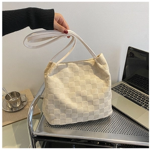 Gros plan d'un sac cabas tissé beige au motif damier dans un décor de vie moderne