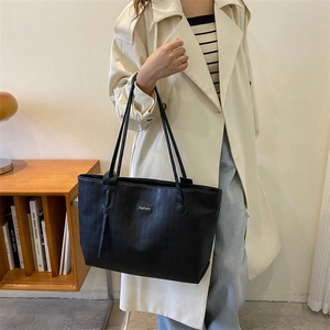 Large black tote bag with quilted texture shown on a shoulder model for urban commute