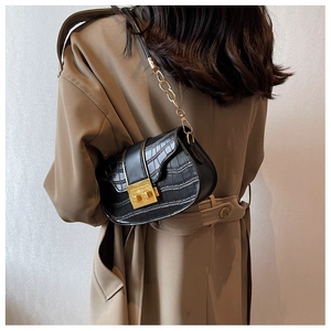 Detail showing black crocodile pattern PU leather bag with gold buckle on trench coat