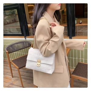 Close-up of white quilted leather crossbody bag with gold chain strap on model