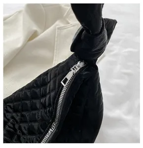 Close-up of silver metal zipper detail on black quilted crossbody bag with soft texture