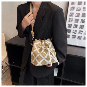 Close-up of khaki bucket bag with white quilted pattern on a model in modern interior