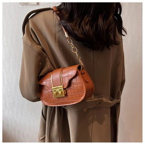 Brown crocodile embossed crossbody bag with gold twist lock shown on model's shoulder