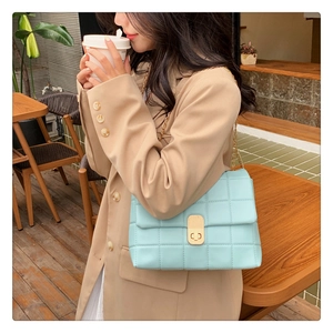 Detail of light blue quilted chain bag with gold hardware in an outdoor cafe setting