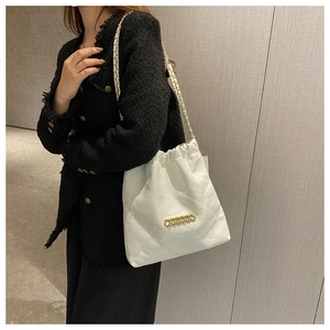 Detail shot of white quilted leather bucket bag with gold chain strap on a model