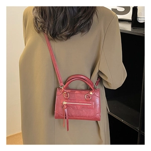 Mini borsa moto vintage rossa con nappe lunghe e finiture dorate sulla modella