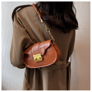 Detailed side view of a brown crocodile pattern crossbody bag with gold chain strap
