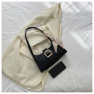 Detail of black crocodile texture underarm bag with gold buckle and silk scarf