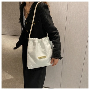 Modern white quilted shoulder bag with gold chain strap detail on female model
