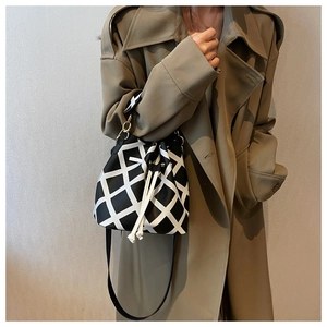 Close-up of black and white geometric lattice bucket bag with gold-tone hardware detail