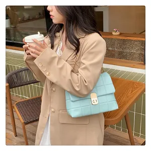 Close-up of a light blue quilted chain bag with gold buckle worn by a model outdoors