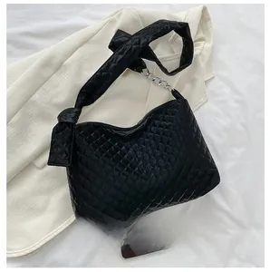 Close-up of black quilted hobo bag with knotted strap and phone for size comparison
