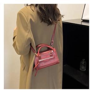 Dettaglio della mini borsa a mano rosso scuro con tasca a zip e tracolla regolabile