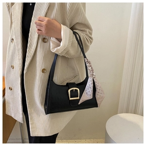 Detail of black crocodile texture bag with gold buckle and decorative silk scarf