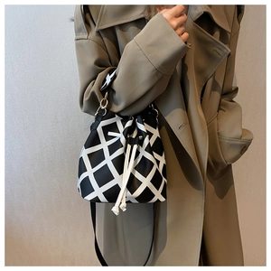Detail of black and white checkered bucket bag with white drawstring and leather strap