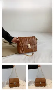 Detail of brown quilted chain bag with gold metal lock and faux leather texture