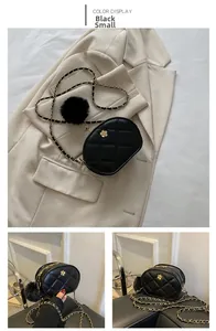 Detail of black quilted leather mini oval bag with gold hardware and pompom charm