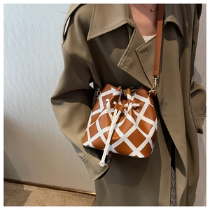 Brown and white quilted bucket bag with drawstring closure and crossbody strap