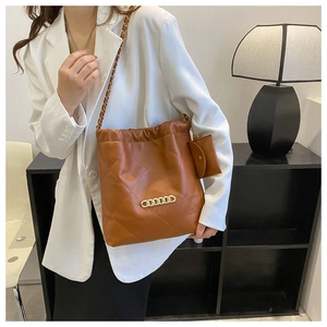 Brown quilted bucket bag with gold chain detail and small coin purse on a model