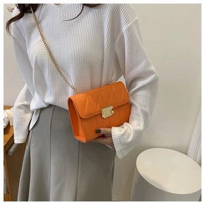 Detail of orange crossbody bag with geometric quilted pattern and gold chain strap