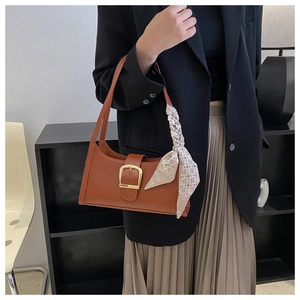 Detailed view of brown underarm bag with gold square buckle and decorative silk scarf