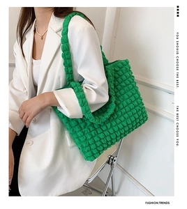 Borsa tote verde con trama a bolle indossata da una modella in uno studio minimal