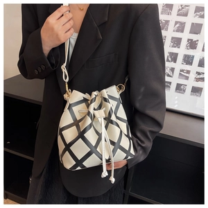 Detail of minimalist bucket bag featuring black diamond lattice pattern and drawstring closure