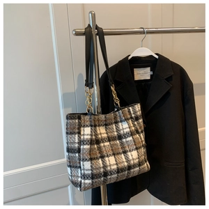 Détail du sac cabas en tweed à carreaux montrant les chaînes dorées et les anses en cuir