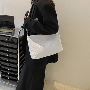 Detailed view of white quilted shoulder bag with large diamond stitching and soft texture