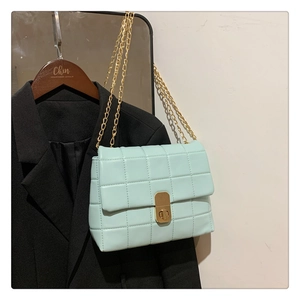 Detailed view of mint green quilted crossbody bag with gold chain strap and metal lock