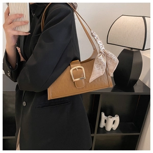 Detail of brown crocodile pattern shoulder bag with silk scarf and gold buckle