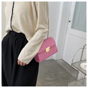 Detailed close-up of pink quilted crossbody bag with golden chain and metallic lock