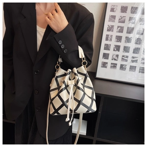 Close-up of beige quilted bucket bag with black grid pattern and gold hardware