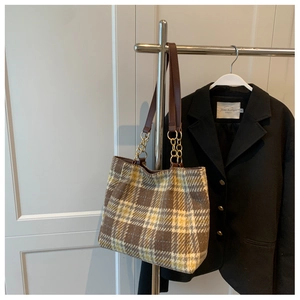 Sac fourre-tout à carreaux avec bandoulière en cuir et chaîne sur un cintre