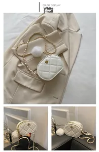 Detail view of white quilted oval crossbody bag with gold floral hardware and chain strap