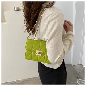 Detail of neon green quilted crossbody bag with gold chain strap and metallic clasp