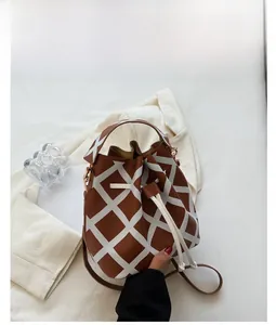 Top view of brown quilted bucket bag with wide handle and white drawstring closure