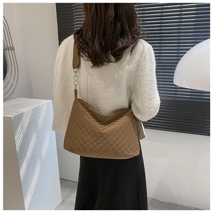 Detailed view of brown quilted tote bag with silver chain and wide shoulder strap