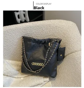 Close-up of black quilted tote bag with chunky gold chain detail and detachable coin purse