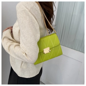 Detail of light green quilted crossbody bag with white stitching and gold chain strap